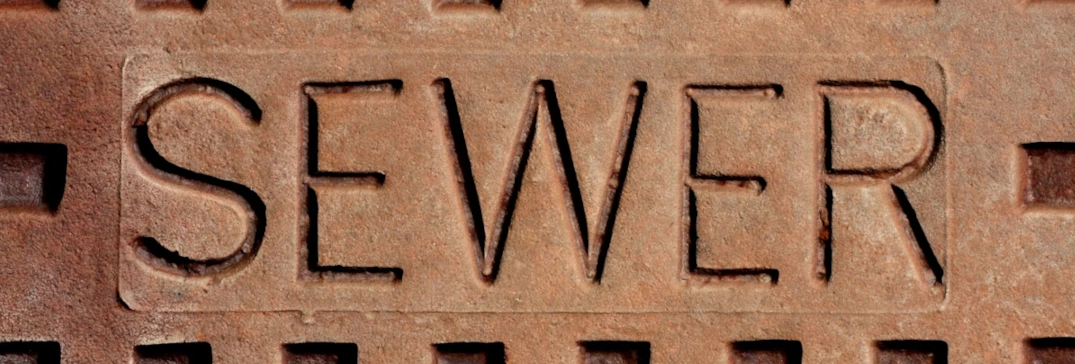 The word sewer displayed on a manhole lid where sewage would come from